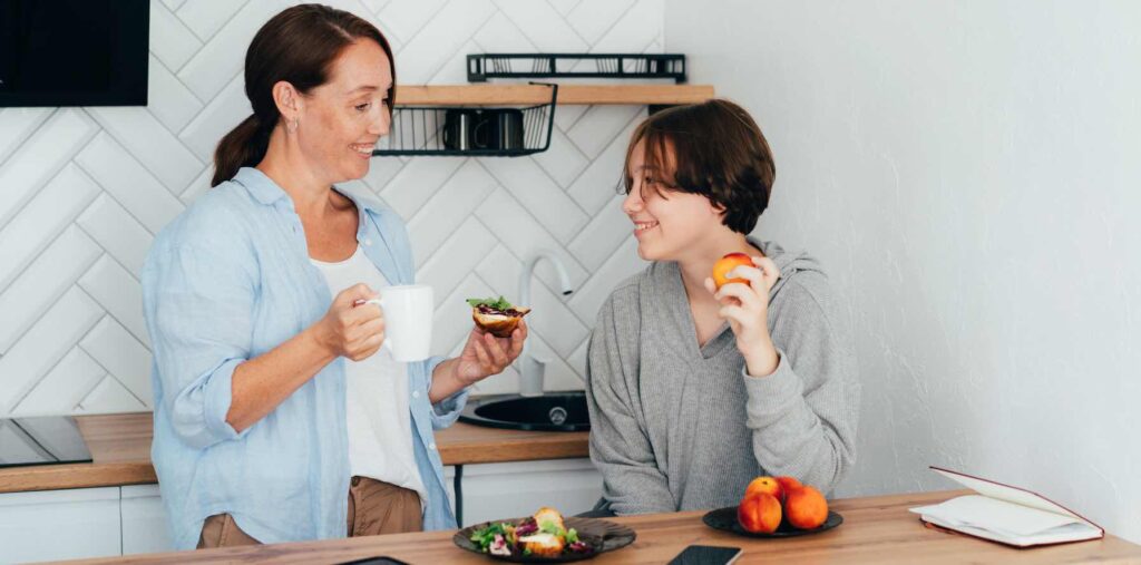 mother talking to teenager eating a snack