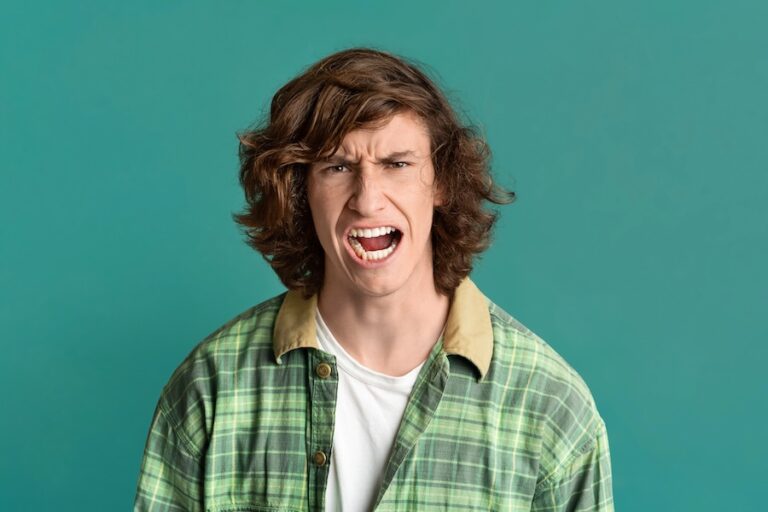 Young guy with furious facial expression on green color background